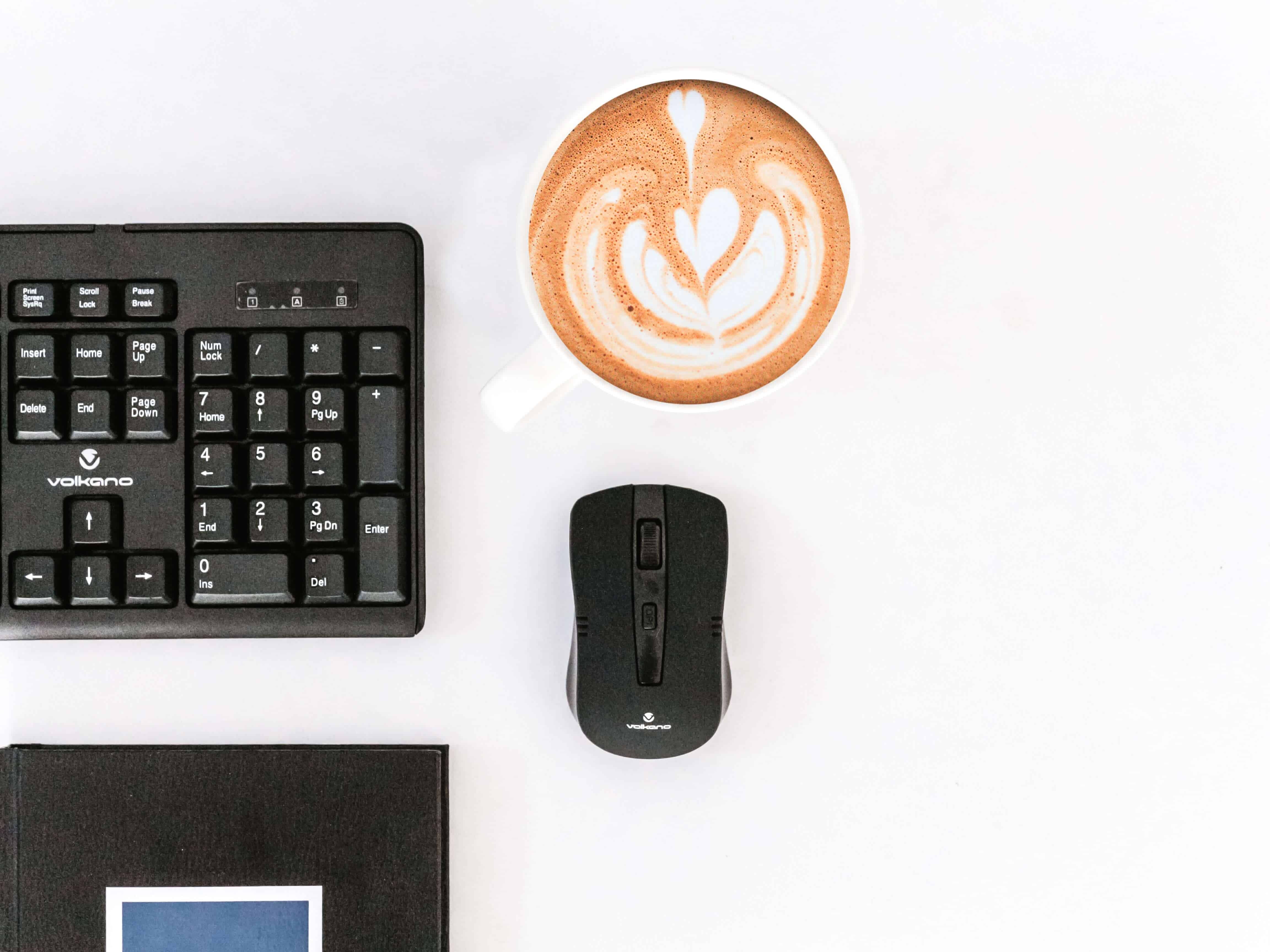 A computer mouse on a table with a cup of coffee.