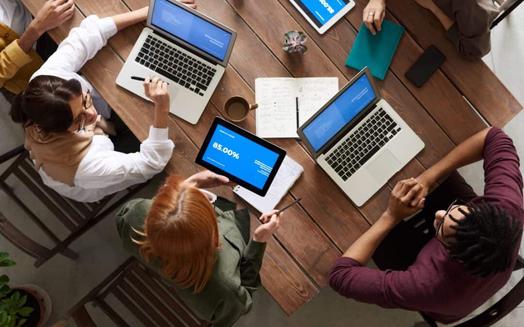 A team discussing data, reports, and laptops around a work table.