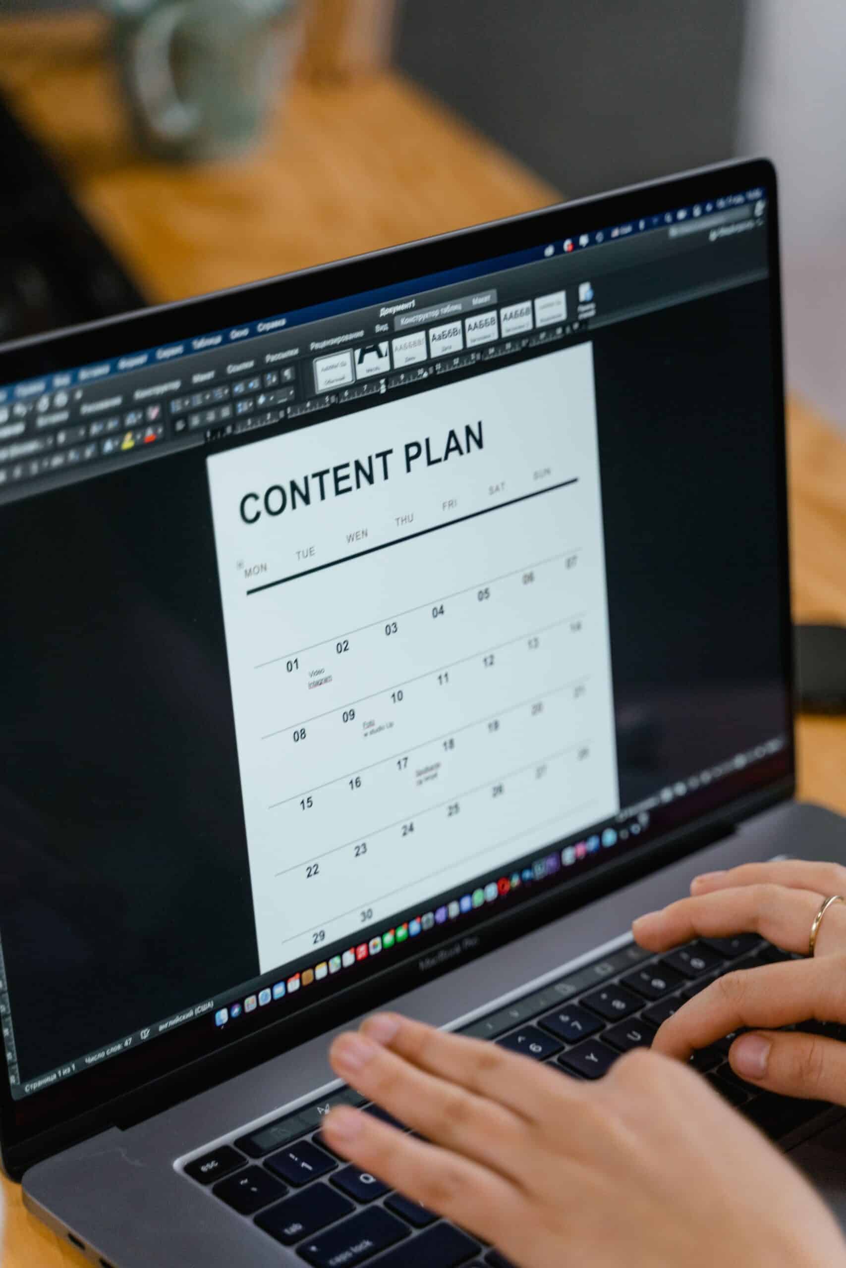 Hands typing on a laptop displaying a structured content plan.